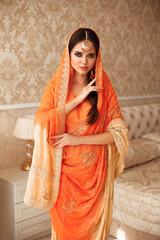 Portrait of beautiful indian girl in traditional saree in luxury interior. Young hindu woman model with kundan golden jewelry set. Indian costume lehenga choli. - 396975054