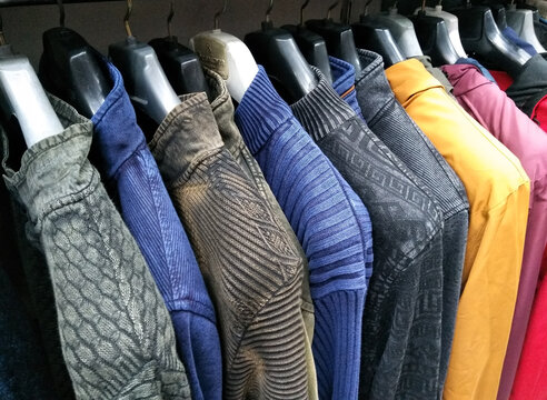 multi color dress sherwani kurta hanging from hangar in a garment shop for sale