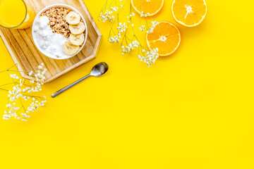 Healthy granola with banana and orange juice for colorful breakfast on yellow background top view mock-up