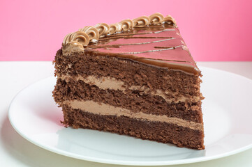 a piece of chocolate cake on white plate on white table and pink  background