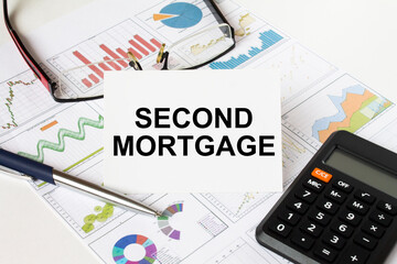 White card with text Second Mortgage it is lies on financial charts with a calculator and eyeglasses