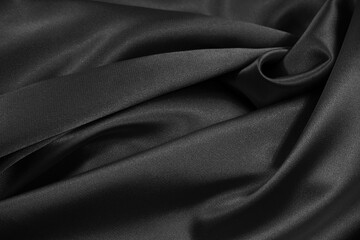 Black satin background. Crumpled shiny fabric texture background. Black elegant silk background.