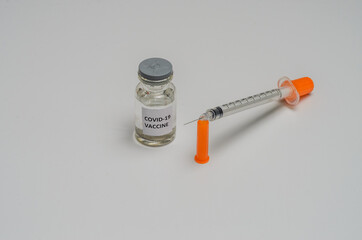 Ampoule with covid-19 coronavirus vaccine and syringe for injections on a white background