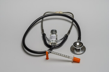 Ampoule with covid-19 coronavirus vaccine and syringe for injections on a white background