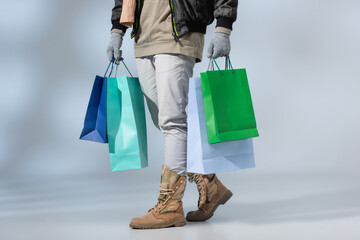 cropped view of stylish man in winter outfit holding shopping bags on grey © LIGHTFIELD STUDIOS