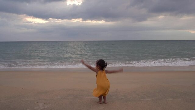 Happy little asian girl playing on the Mai Khao Beach in Phuket.