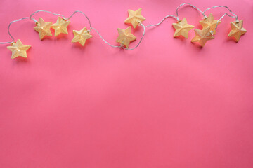 Obraz na płótnie Canvas Christmas decoration. Garland star-shaped lights on pink background