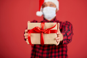 Man in protective face mask and Santa hat with Christmas DIY gift