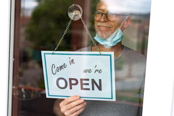 Store owner hanging open sign on window