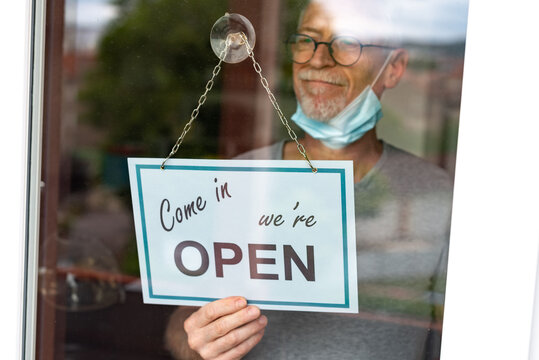 Store owner hanging open sign on window