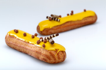 Eclair with custard and lemon glaze on a white background. Confectionery for the sweet tooth.