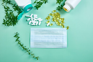 Flat lay of Medical face mask and pills, fish oil, vitamins on blue background, coronavirus