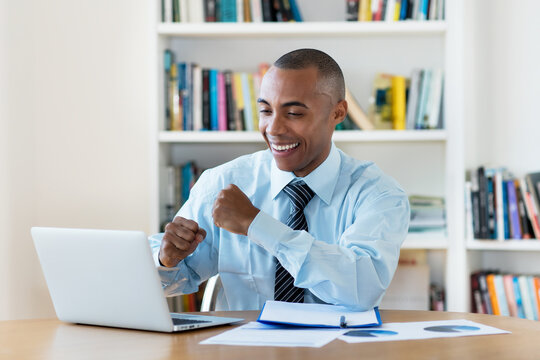 Laughing and cheering african american businessman working at computer