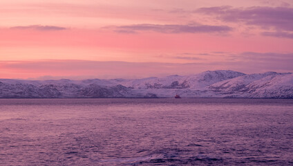 Amazing sunrise polar landscape with white snowy mountain range on the horizon. Arctic ocean panoramic view