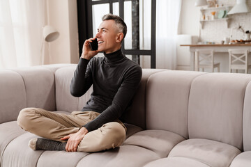 Handsome joyful man smiling and talking on mobile phone