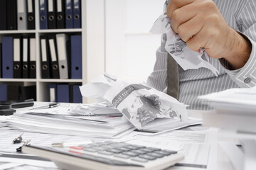 business problem concept - disappointed businessman has trouble and tears up reports