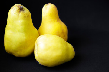 Fresh quince fruits against black background