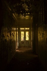 Obraz premium A long corridor, in an old, abandoned building, in the distance, a window through which sunlight enters.