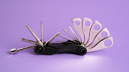 Bicycle bike portable mini multitool repair tools on a purple background. Bike multi tool. Bike repair tool kit.