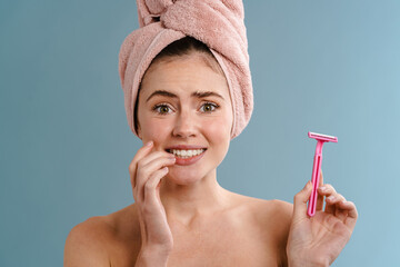 Woman in towel holding blade over blue wall background