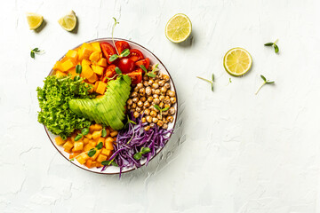 vegan, detox Buddha bowl with avocado, tomato, red cabbage, chickpea, fresh lettuce salad, pumpkin, persimmon. Delicious breakfast or snack on a light background, top view