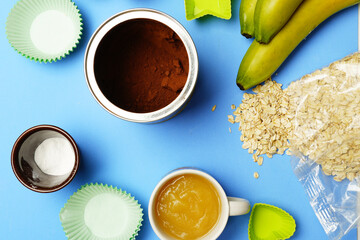 top view of ingredients to make banana cake with cocoa with muffin molds around. pastry kitchen concept. flat lay