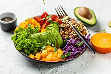 Healthy salad vegan, detox bowl with avocado, tomato, red cabbage, chickpea, fresh lettuce salad, pumpkin, persimmon