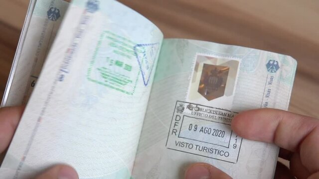 Reisepass mit Stempeln in der Hand halten und umbl&auml;ttern