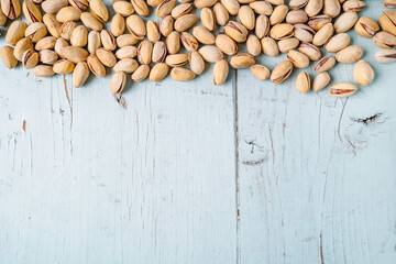 A row of pistachios on a blue wooden background