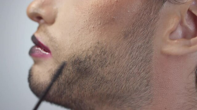 Extreme close up of dyeing beard of male model with black mascara