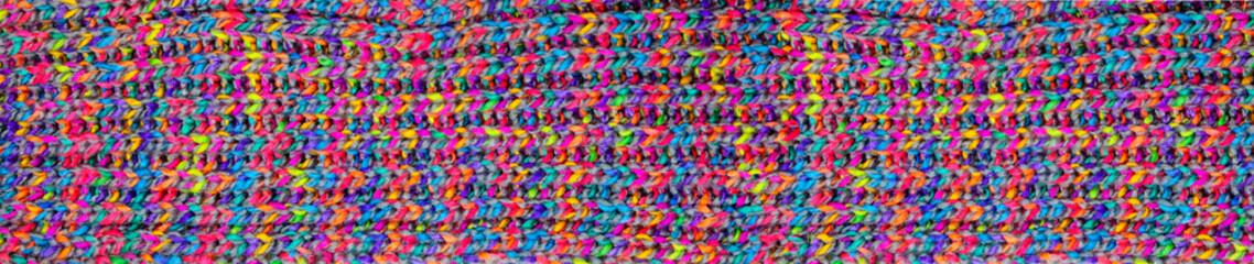 Detail of knitwear of a shawl. knitted fabric texture. Texture of mulicolored knit scarf. Large knitting. panoramic web banner Top view