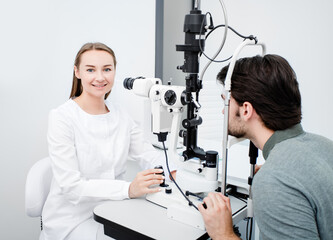 Optometrist woman looking at camera during eye examination of a male patient with special...