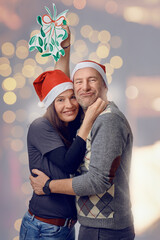 Middle-aged happy couple holding a paper concept mistletoe and looking very loved celebrating for christmas