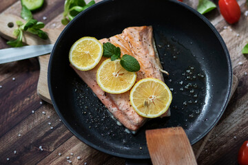 Salmon in a pan with lemon and other vegetables. Salmon on plates