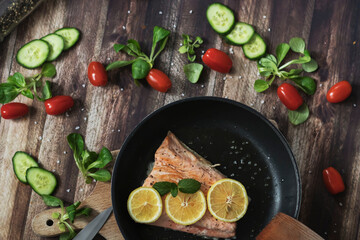 Salmon in a pan with lemon and other vegetables. Salmon on plates