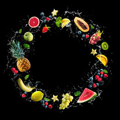 Assortment of fresh fruits and water splashes on black background