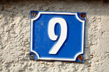 Blaues Hausnummernschild Nummer Neun auf weisser Hauswand, Deutschland, Europa