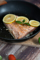 Salmon in a pan with lemon and other vegetables. Salmon on plates