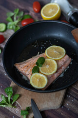 Salmon in a pan with lemon and other vegetables. Salmon on plates