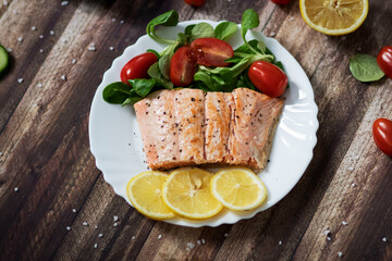 Salmon in a pan with lemon and other vegetables. Salmon on plates