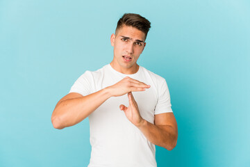 Young caucasian handsome man isolated showing a timeout gesture.