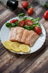 Salmon in a pan with lemon and other vegetables. Salmon on plates