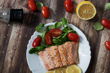 Salmon in a pan with lemon and other vegetables. Salmon on plates