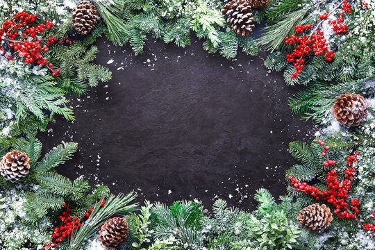 Christmas and New Year background with fir branches and snowfall on dark stony board