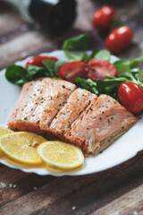 Salmon in a pan with lemon and other vegetables. Salmon on plates
