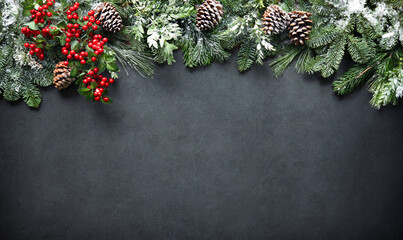 Christmas and New Year background with fir branches and snowfall on dark stony board