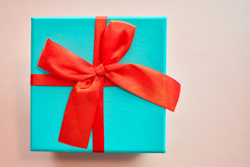 Light blue gift box with a red bow on a pink background. space for text, top view