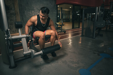 Obraz na płótnie Canvas fitness man with leg training machine in gym