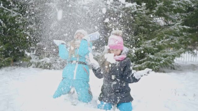 Two girls throw snow over themselves