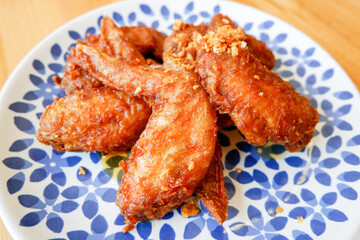 Fried chicken wings with garlic on plate and wooden table food.